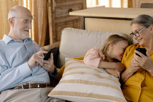 A warm family moment with grandparents and granddaughter using smartphones on a cozy sofa.